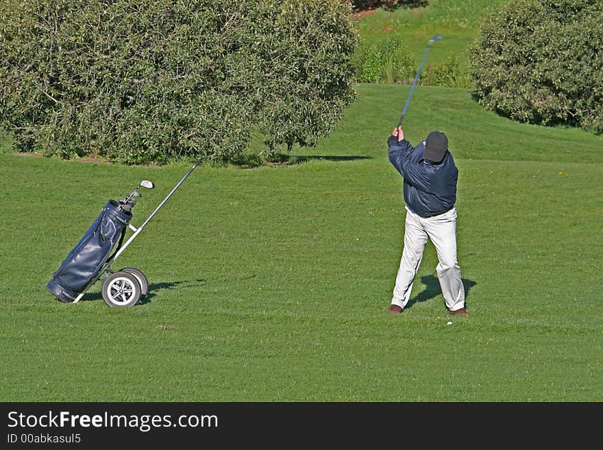 Golfer at top of swing on a golf course