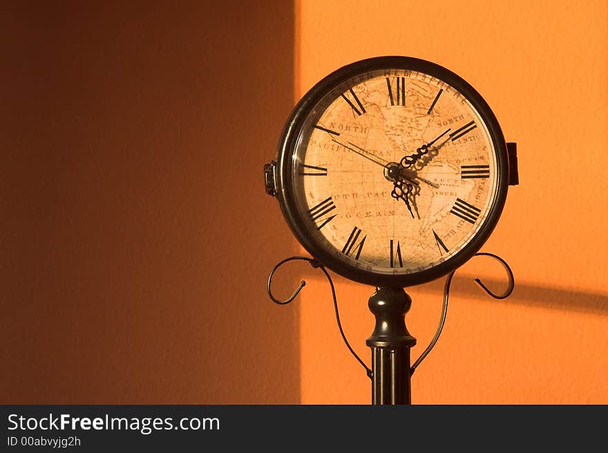 An antique clock with map face on a warm orange background.  Horizontal format. An antique clock with map face on a warm orange background.  Horizontal format.