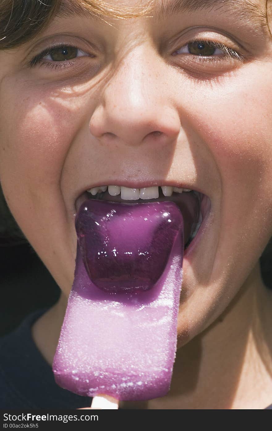 Boy eating a purple bendy iceblock - more like frozen jelly than ice. Boy eating a purple bendy iceblock - more like frozen jelly than ice