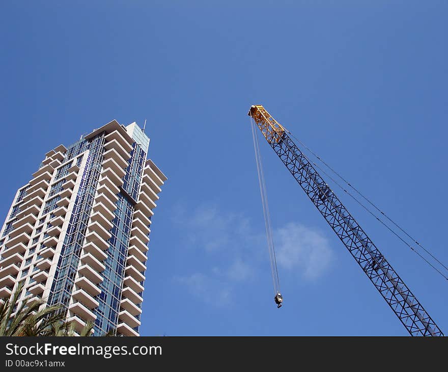 Crane against a blue sky next to a modern building