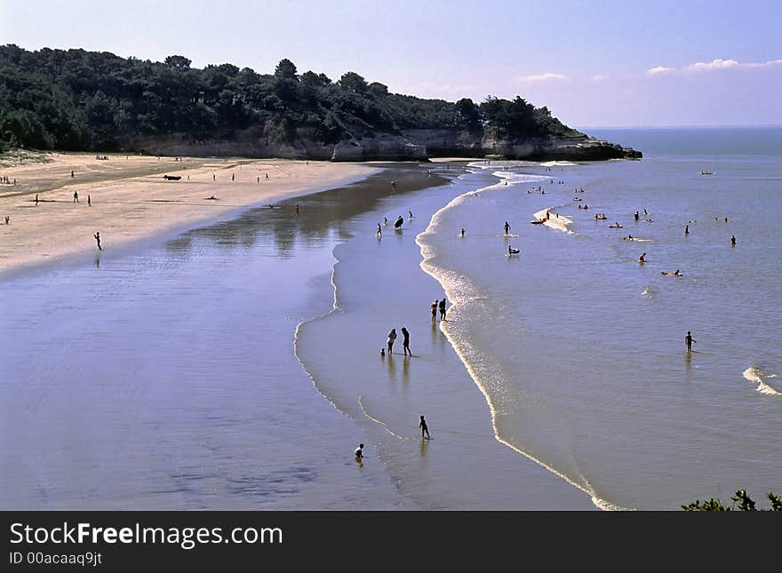 From a rock above the beach a view of different leisure activities in summer at low tide. From a rock above the beach a view of different leisure activities in summer at low tide