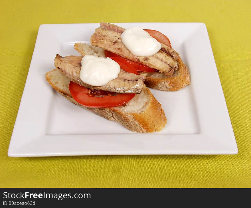 Two pieces of bread with mackerel and mayonnaise on white platter. Two pieces of bread with mackerel and mayonnaise on white platter