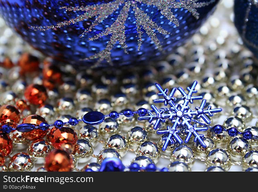 Glass christmas sphere with a pattern and a snowflake of dark blue color on a background of a beads