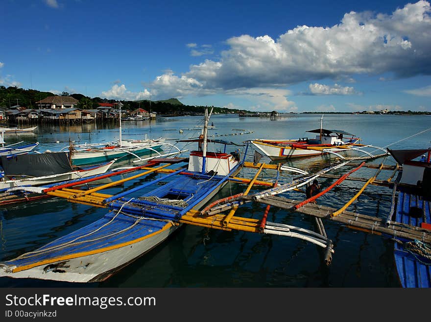 Southeast Asian small village port with fishermen's boats, village and cloudscape. Southeast Asian small village port with fishermen's boats, village and cloudscape.