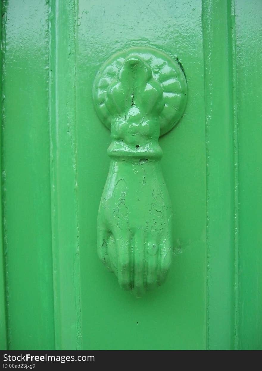 Antique, green painted knocker on old wooden door with same color. Antique, green painted knocker on old wooden door with same color