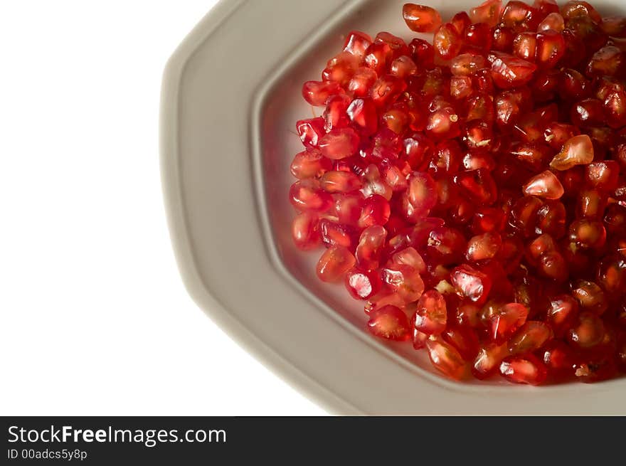 Pomegranate grains on dish isolated on white