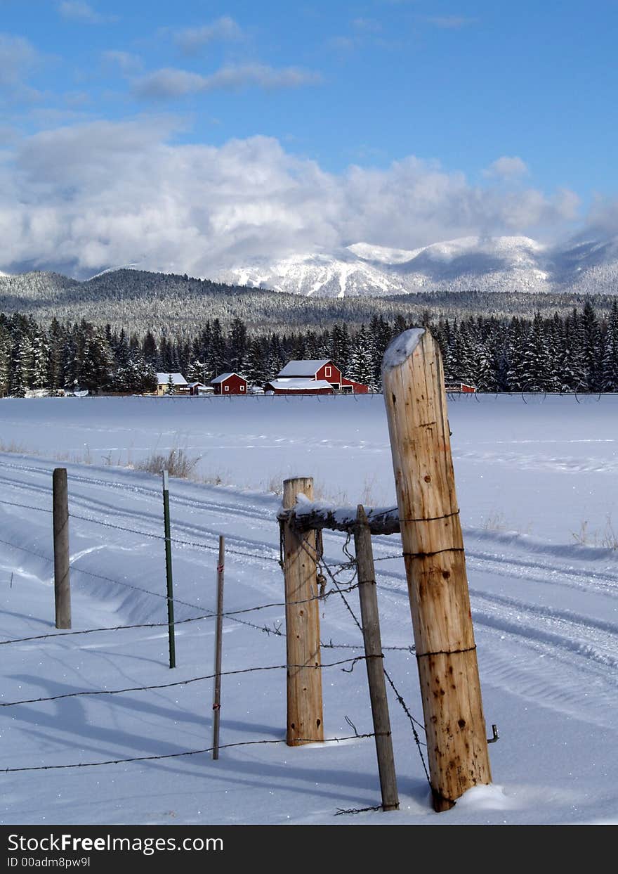 This image of the red farm house and red barn nestled in the snowcovered trees was taken in western MT. This image of the red farm house and red barn nestled in the snowcovered trees was taken in western MT.