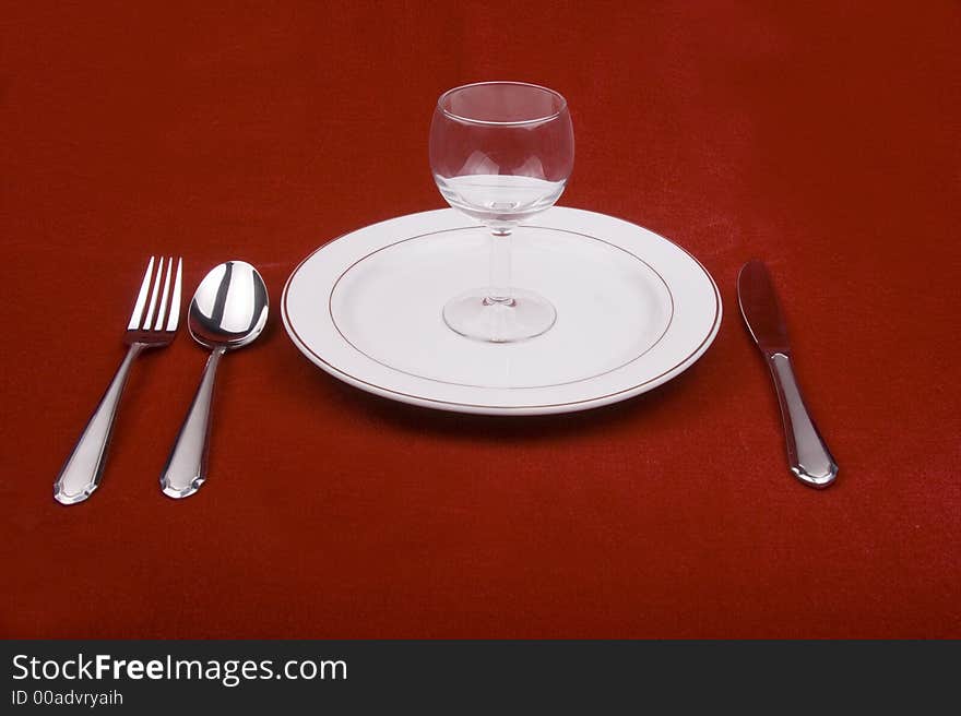 Place setting of a dinning set in red background.