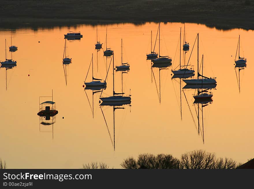 Yachts anchored on the Gariep dam in South Africa. The water is as smooth as a mirror and the masts and rigging reflects tranquilly in the tinted surface of the water. Yachts anchored on the Gariep dam in South Africa. The water is as smooth as a mirror and the masts and rigging reflects tranquilly in the tinted surface of the water.