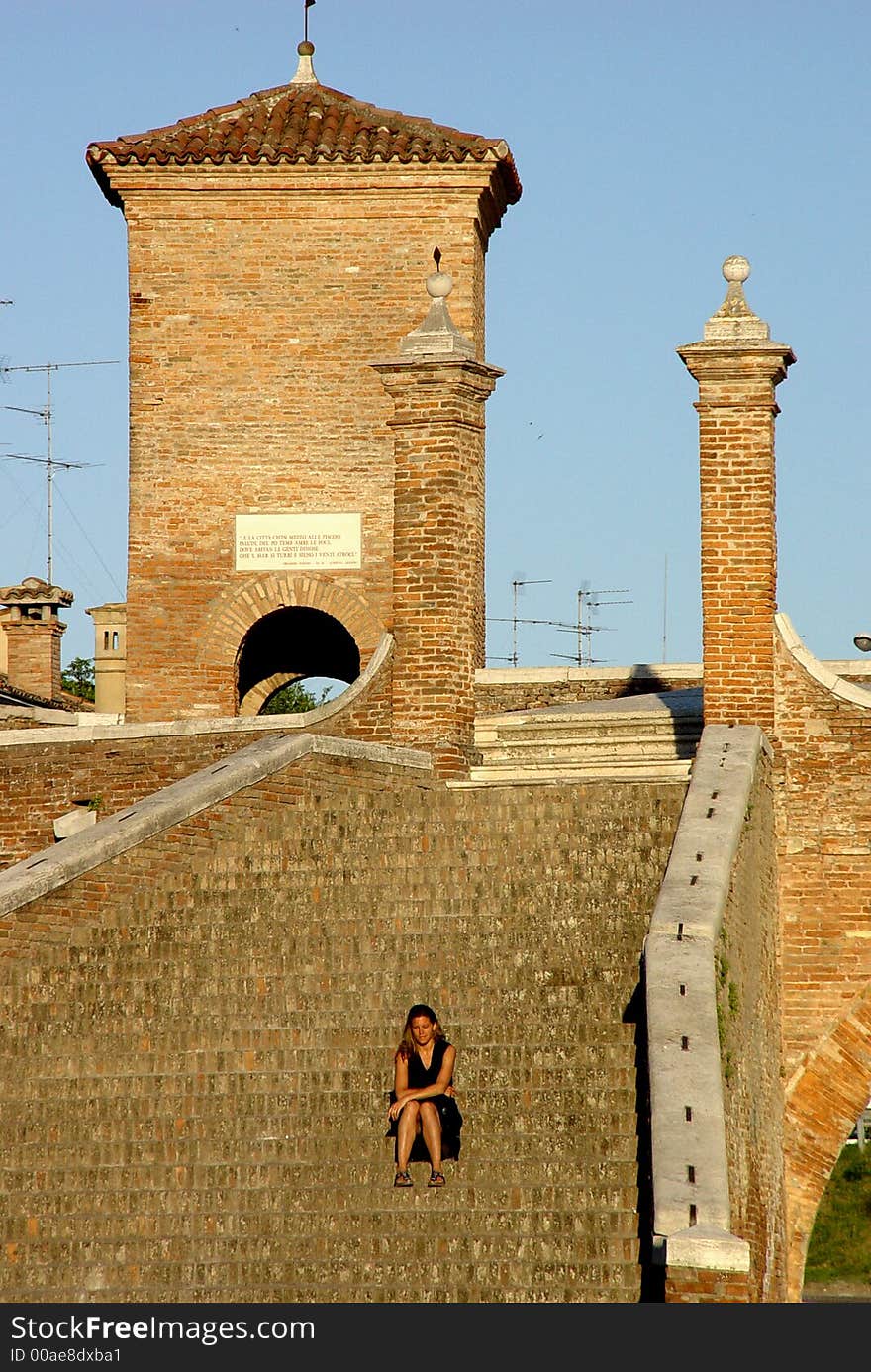 A beautiful girl takes a break on the steps of a picturesque bridge in northern Italy. A beautiful girl takes a break on the steps of a picturesque bridge in northern Italy