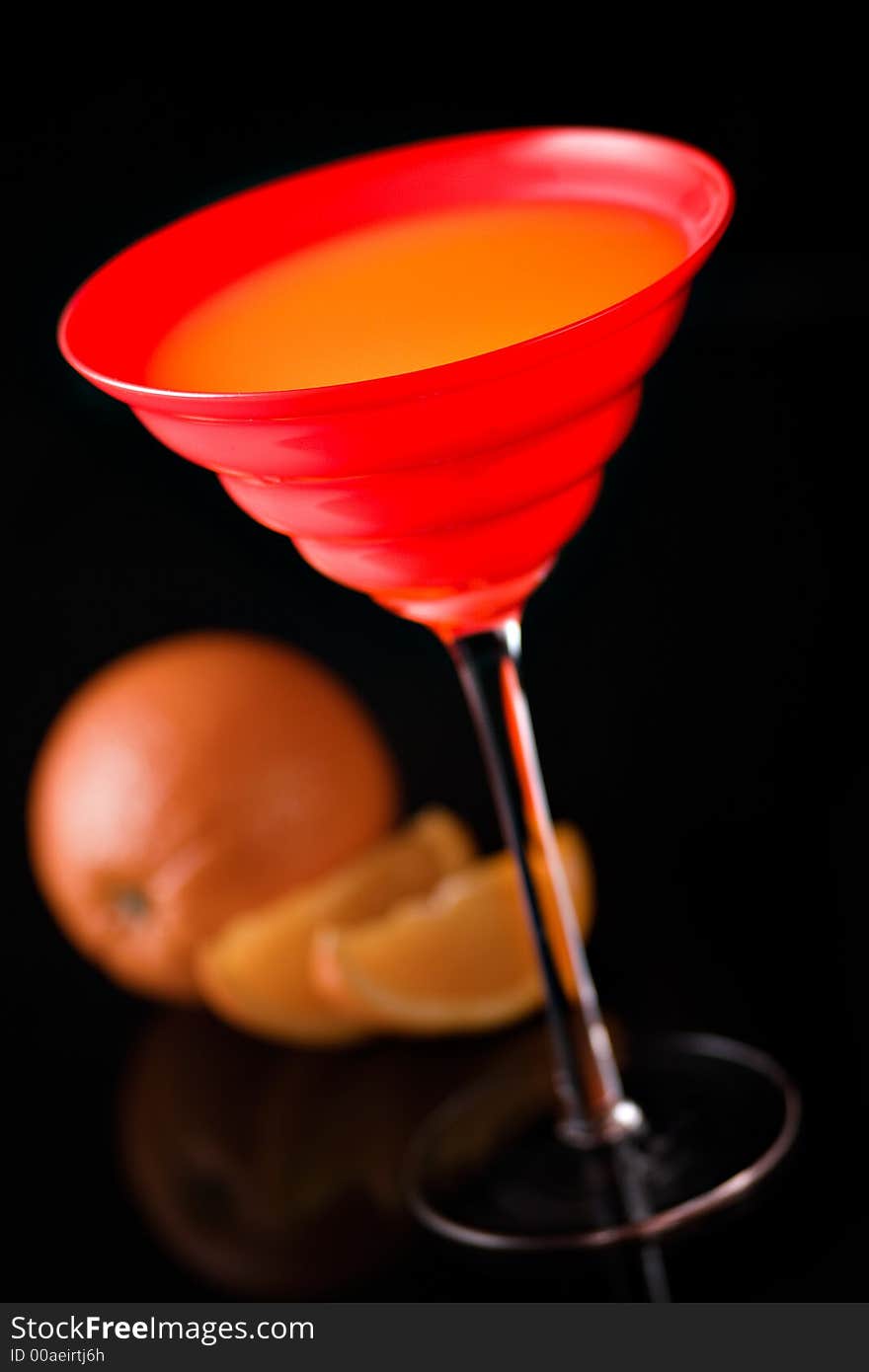 Orange fresh juice in red glass with oranges on background, on black. Orange fresh juice in red glass with oranges on background, on black