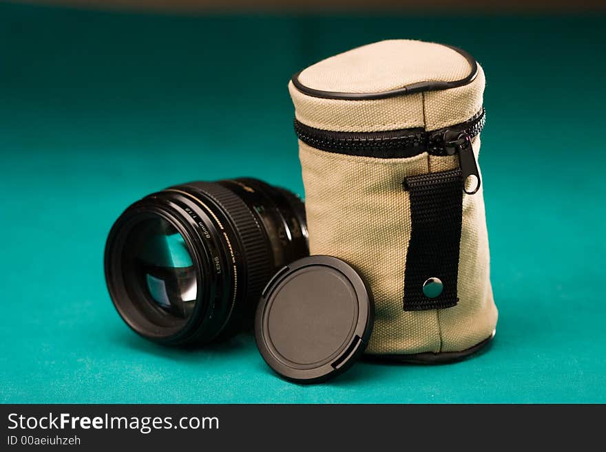 Fast photo lens with cap and pouch on textured background. Fast photo lens with cap and pouch on textured background