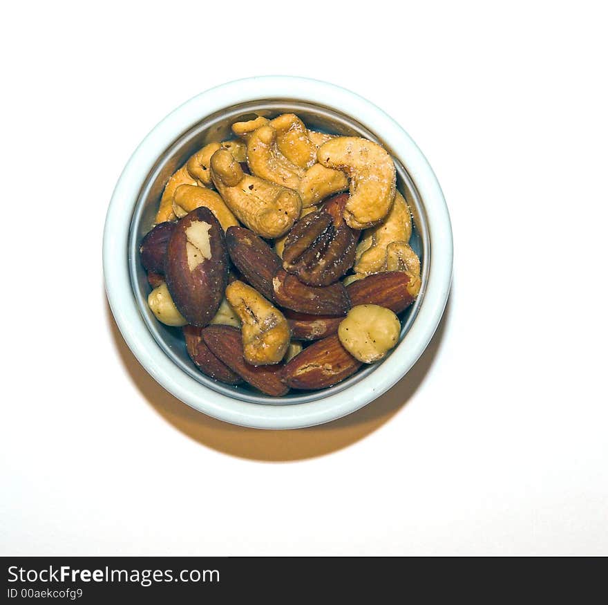 Mixed nuts in a white ceramic cup, on a white background