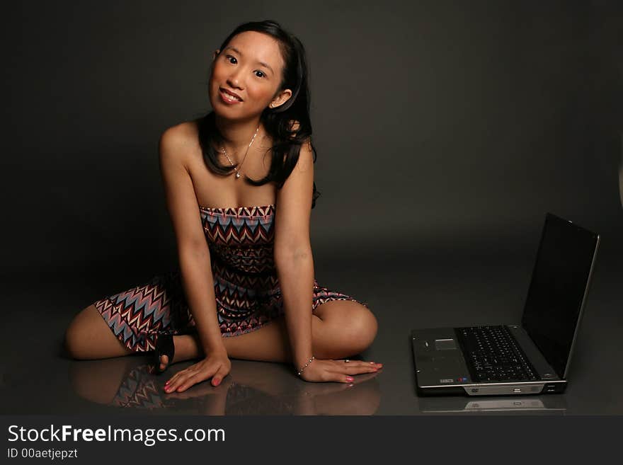 Asian woman sitting next to laptop