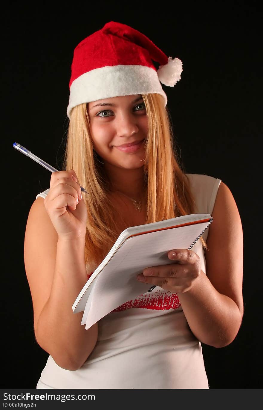 Christmas blonde girl with pencil and bloc notes thinking and writing. Christmas blonde girl with pencil and bloc notes thinking and writing