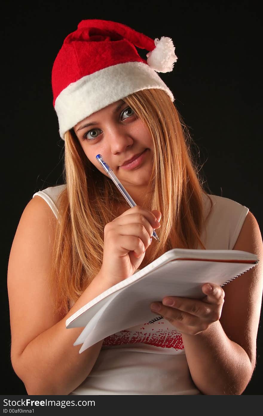 Christmas blonde girl with pencil and bloc notes thinking and writing. Christmas blonde girl with pencil and bloc notes thinking and writing