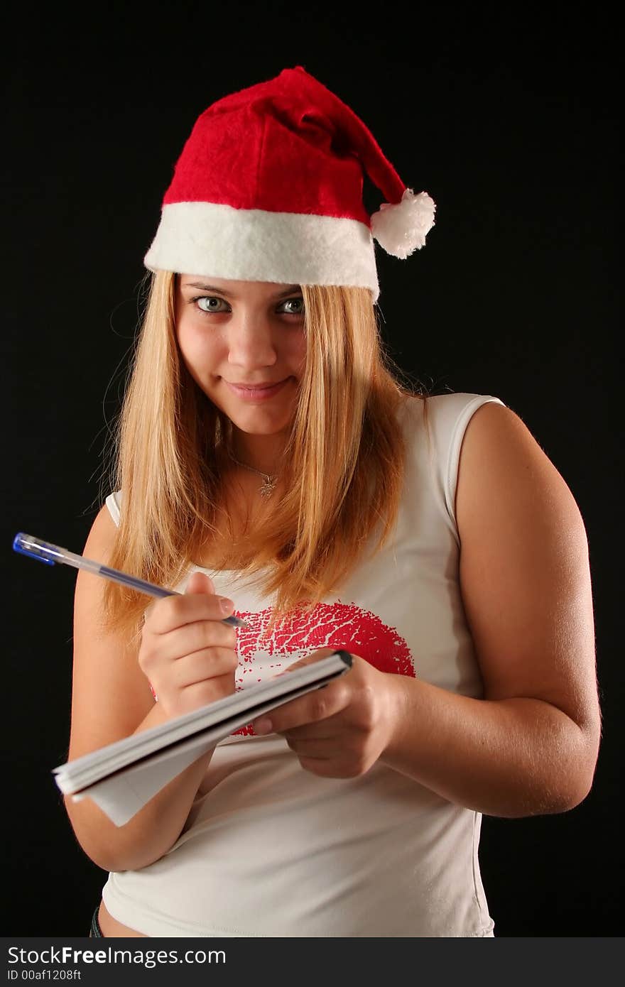 Christmas blonde girl with pencil and bloc notes thinking and writing. Christmas blonde girl with pencil and bloc notes thinking and writing