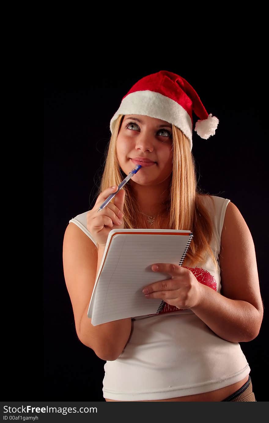 Christmas blonde girl with pencil and bloc notes thinking and writing. Christmas blonde girl with pencil and bloc notes thinking and writing