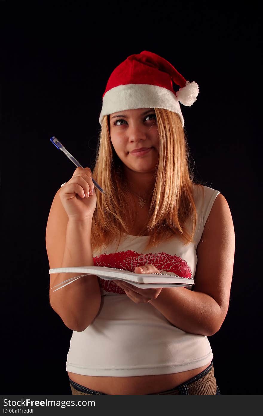 Christmas blonde girl with pencil and bloc notes thinking and writing. Christmas blonde girl with pencil and bloc notes thinking and writing