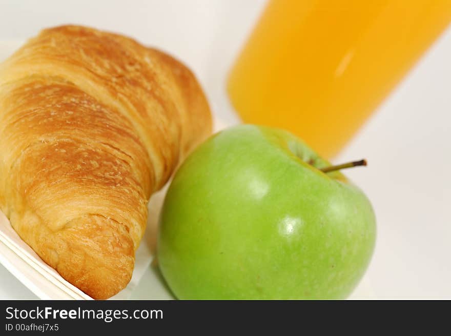 Fresh-baked croissant, orange juice and green apple.  Shallow DOF. Focus on croissant. Fresh-baked croissant, orange juice and green apple.  Shallow DOF. Focus on croissant.