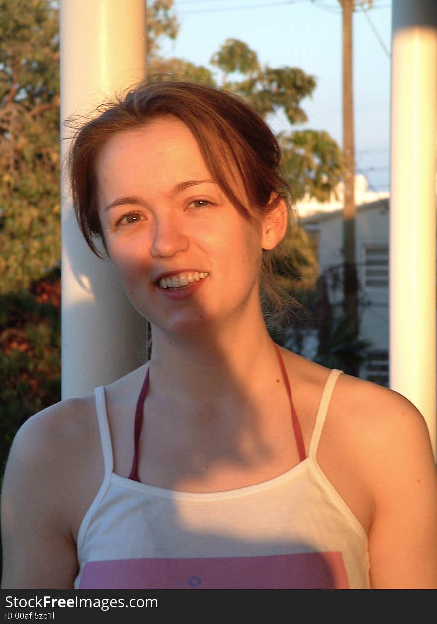 Young Woman Leans Against Pole In Afternoon Sunlight