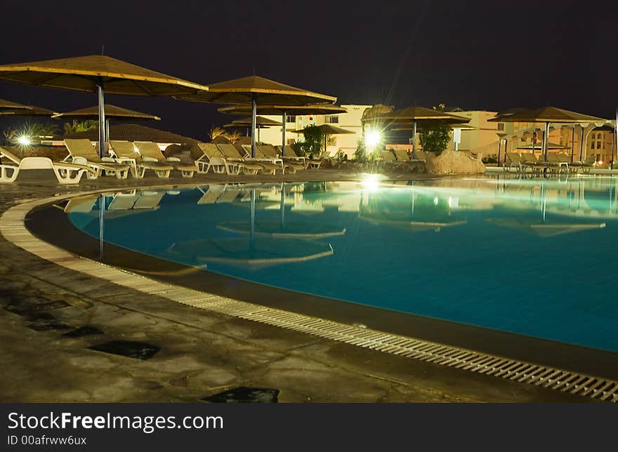 Night picture of rest. swimming-pool, parasols and sunbeds.