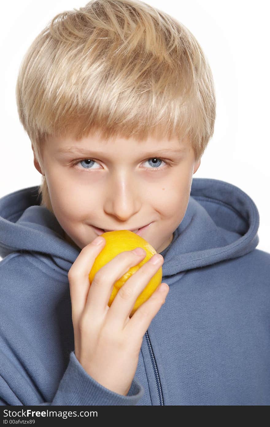 An eleven-year boy eats a lemon and smiles. On white background. An eleven-year boy eats a lemon and smiles. On white background.