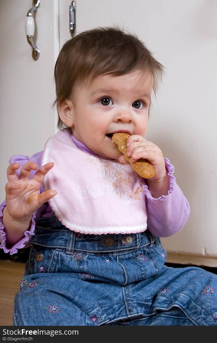 Adorable baby on the kitchen floor enjoying a cookie. Adorable baby on the kitchen floor enjoying a cookie.