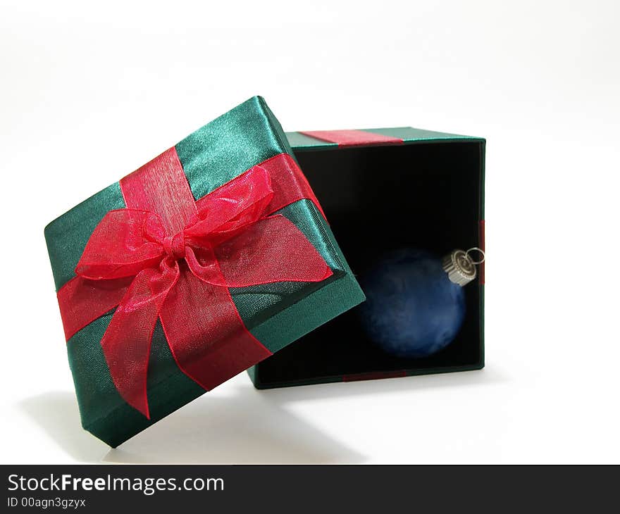 Photo of a green christmas present with a red bow and a blue ornament inside isolated on a white background. Photo of a green christmas present with a red bow and a blue ornament inside isolated on a white background