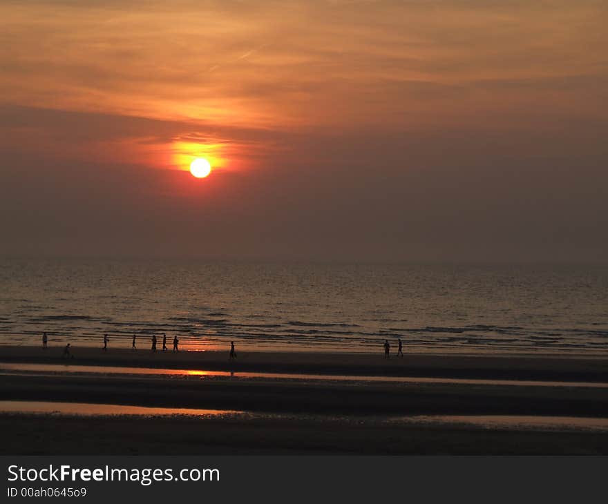 People walking at the beach in the light of a beautiful sunset. People walking at the beach in the light of a beautiful sunset.