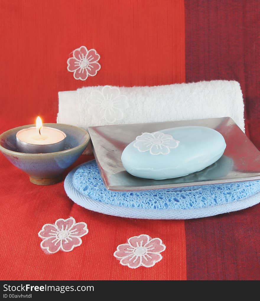 Burning candle and white flowers with soap in a dish