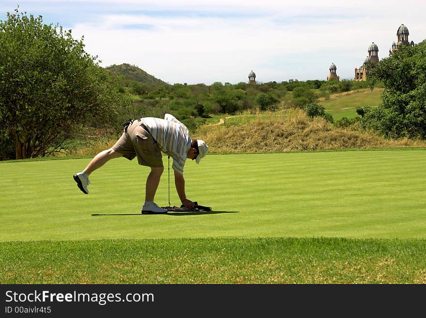 Golfer picking up the towel on the green. Golfer picking up the towel on the green.