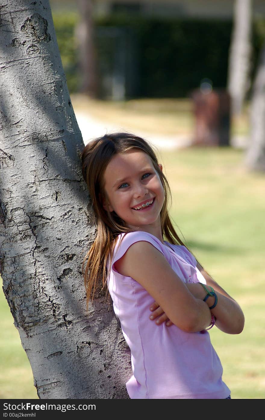 A pretty nine year old girl leaning on a tree in a park. A pretty nine year old girl leaning on a tree in a park.