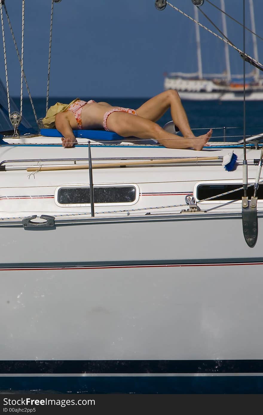 Shot of a waoman on the bow of a sailboat catching some rays. Shot of a waoman on the bow of a sailboat catching some rays.