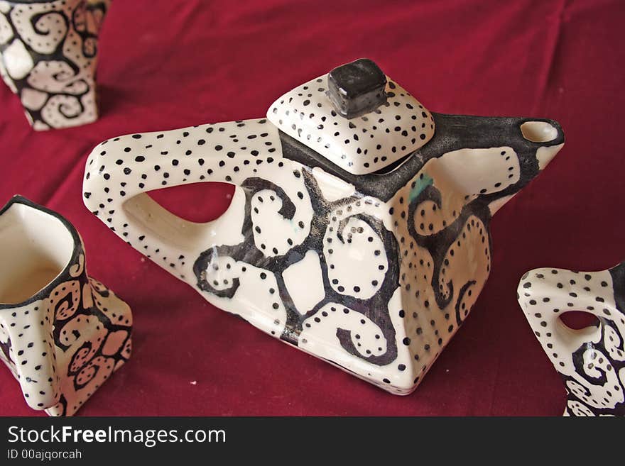 This unusual teapot was exhibited at a centre for the development of young African artists.The teapot has unusually sharp edges, repeated by the dark ethnic pattern painted on it. This unusual teapot was exhibited at a centre for the development of young African artists.The teapot has unusually sharp edges, repeated by the dark ethnic pattern painted on it.