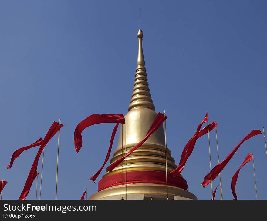 Golden cheddi with red flags at Buddhist temple in Thailand. Golden cheddi with red flags at Buddhist temple in Thailand