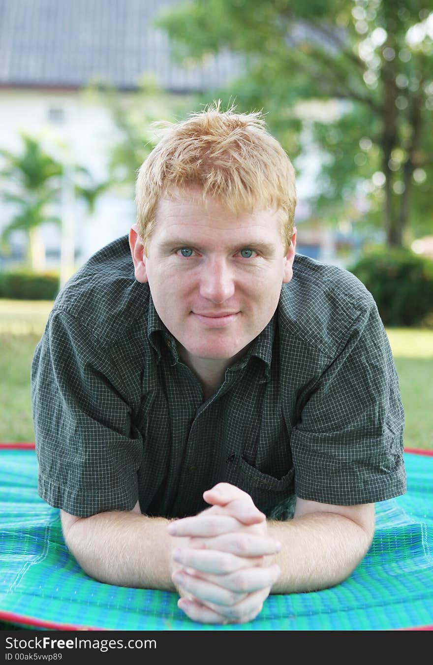 Man relaxing at the park on a green mat