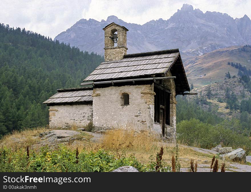 Very little mountain chapel on wood and rocks background in southern french Alps