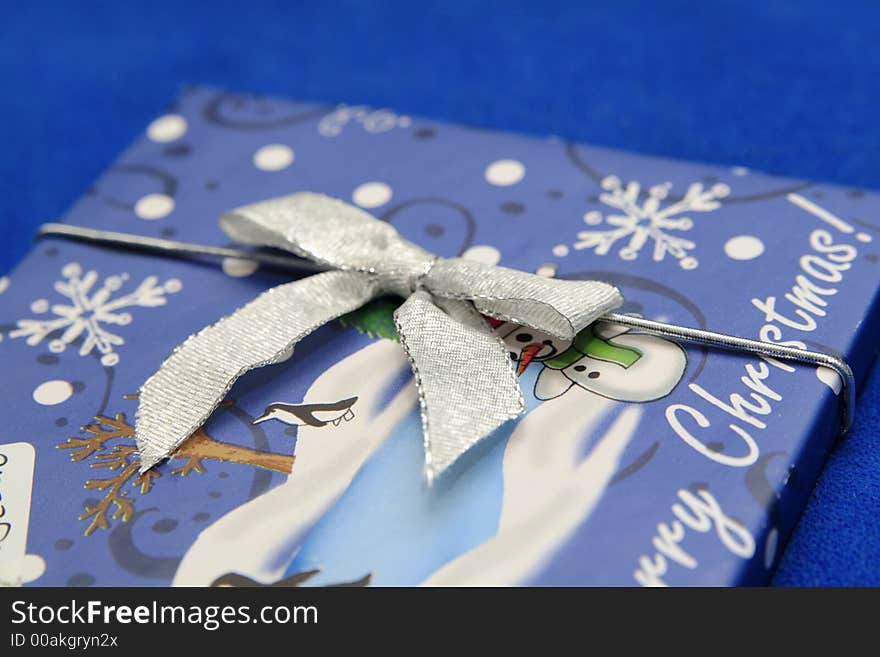 Wrapped blue christmas present with close up of silver bow