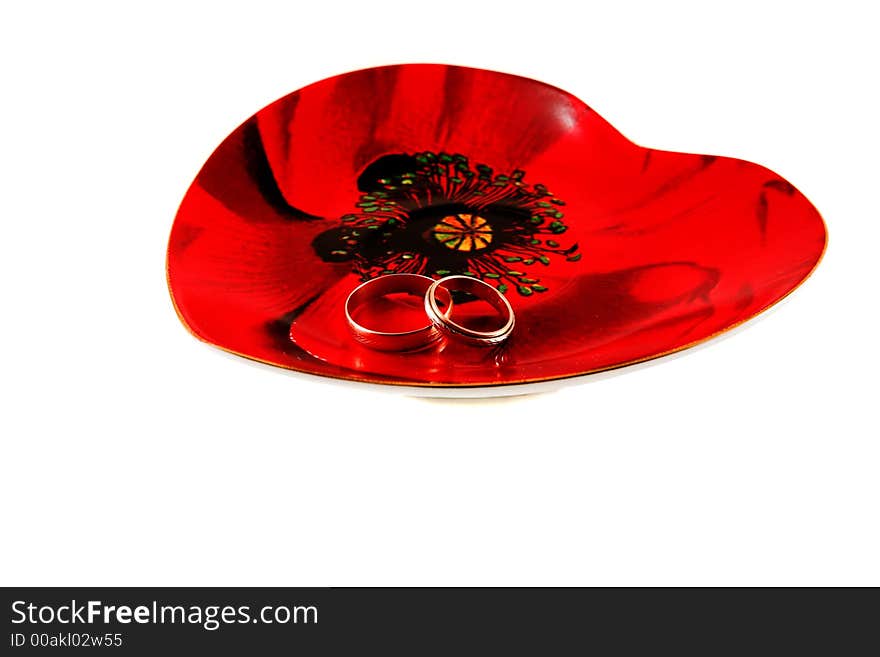 Two wedding rings on the heart-shaped plate isolated. Two wedding rings on the heart-shaped plate isolated