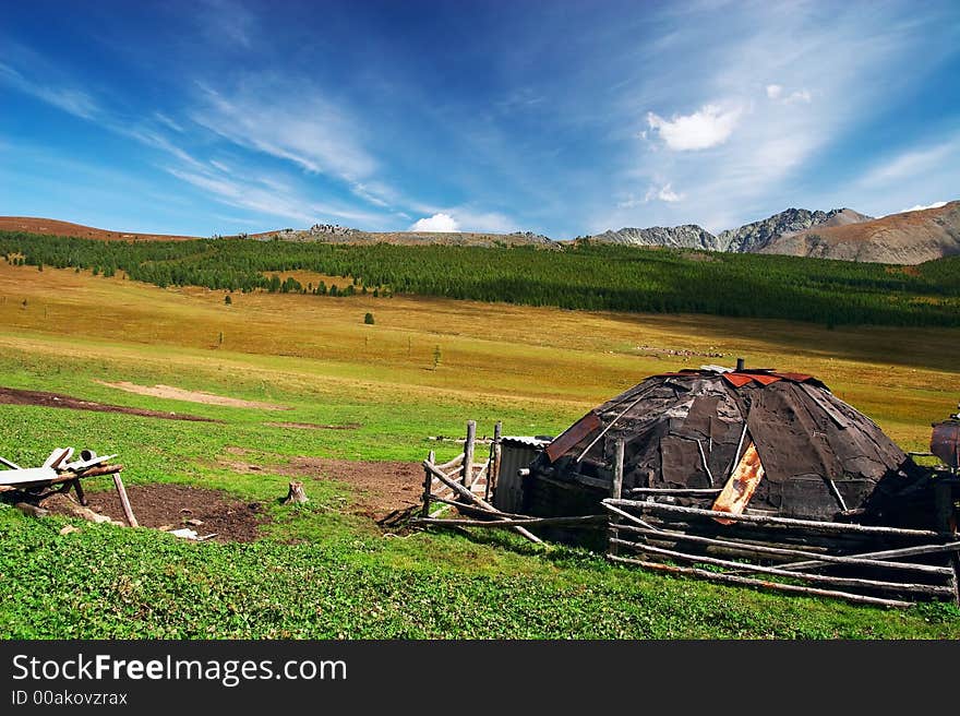 Old house, blue sky and mountains. Altay. Russia.