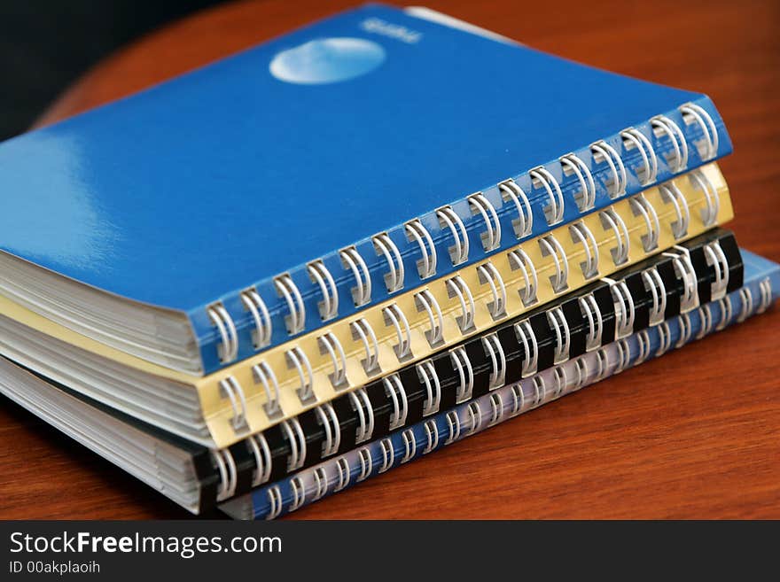 A pile of diaries lying on a wooden office desk. A pile of diaries lying on a wooden office desk