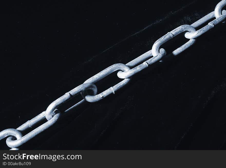 Long heavy chain, silver-colored against black-velvet, going diagonally over image. Long heavy chain, silver-colored against black-velvet, going diagonally over image