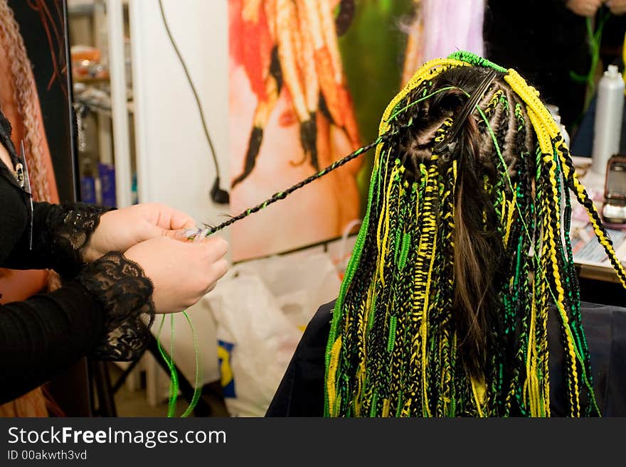 Woman coiffure. Hairdresser does hairstyle from pigtail.