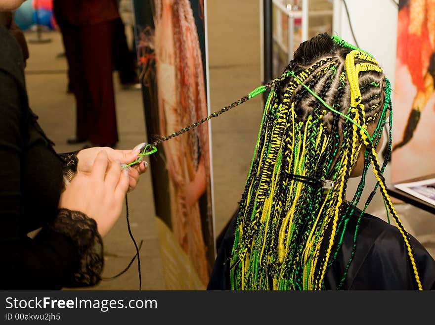 Woman coiffure. Hairdresser does hairstyle from pigtail.