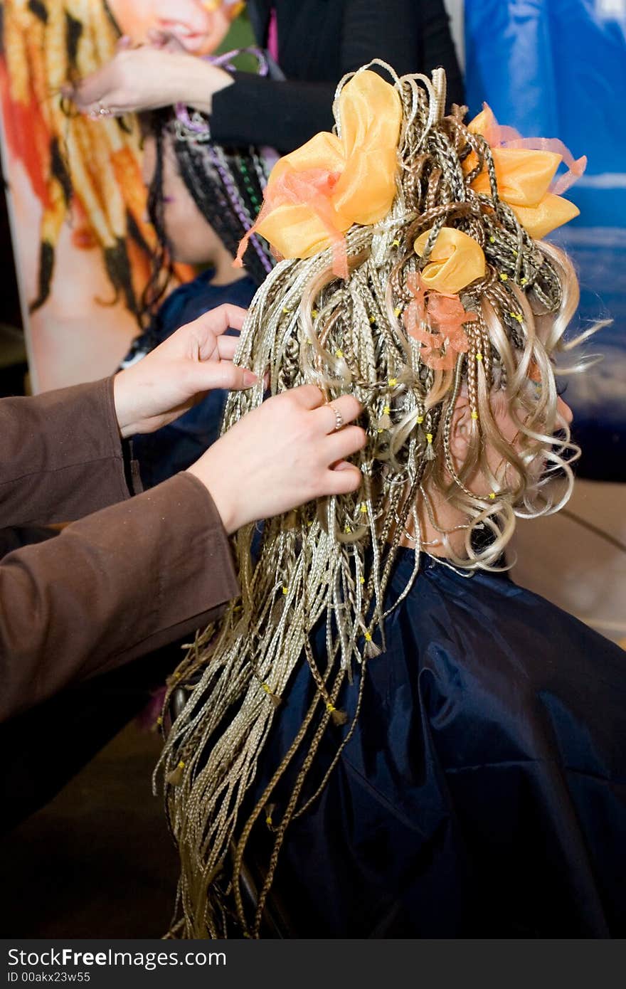 Woman coiffure. Hairdresser does hairstyle from pigtail.