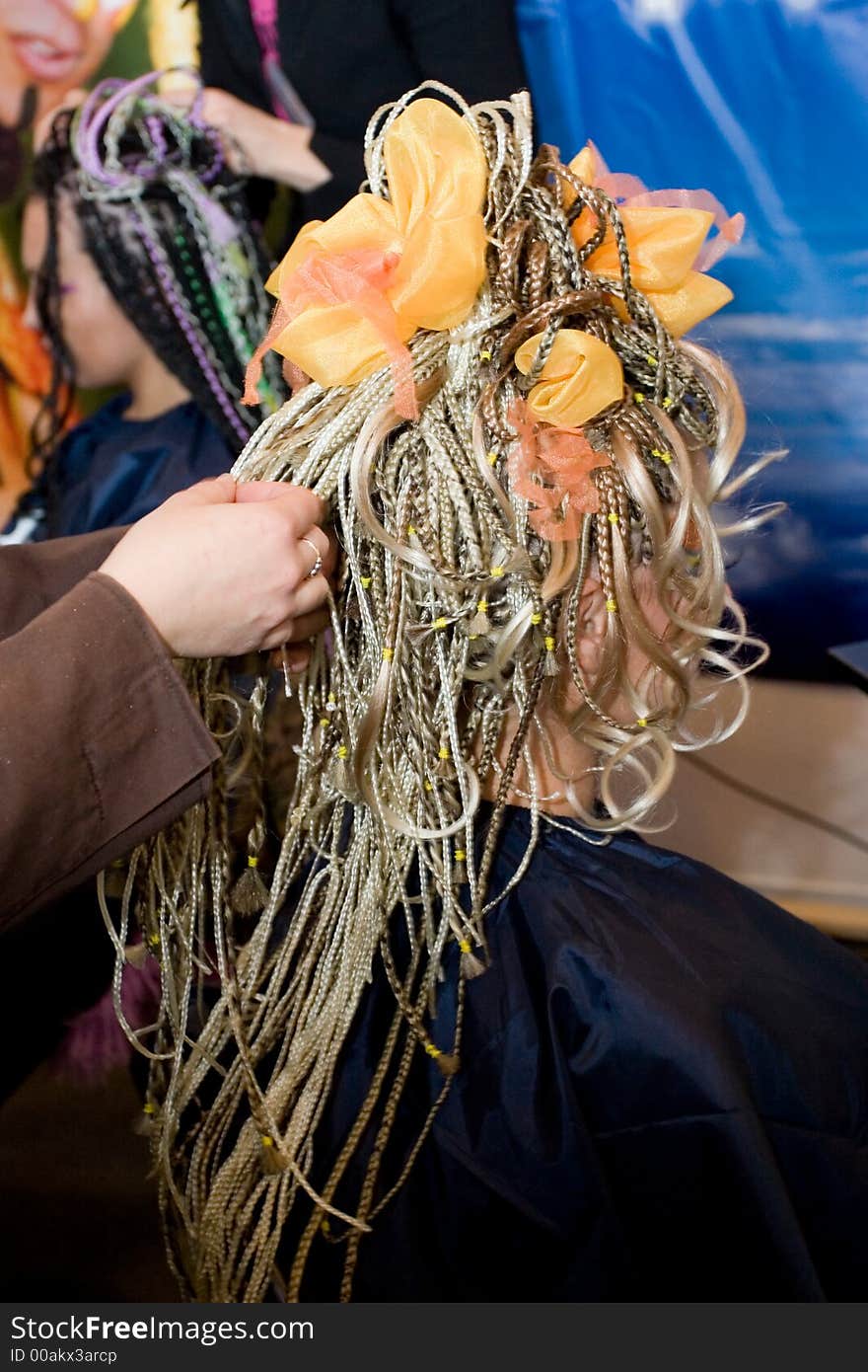 Woman coiffure. Hairdresser does hairstyle from pigtail.