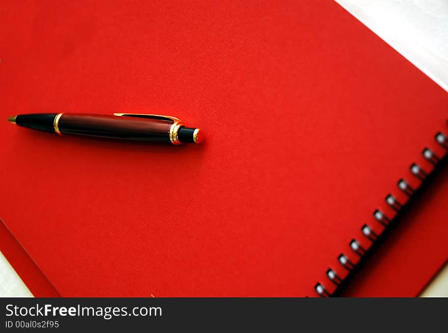 Red note book and pen on the table