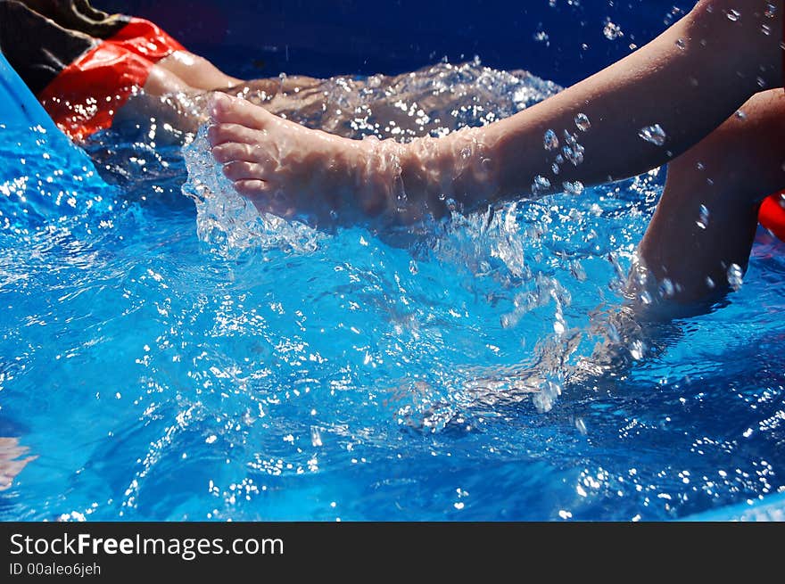 Two boys playing and kicking in a kiddie pool. Two boys playing and kicking in a kiddie pool.