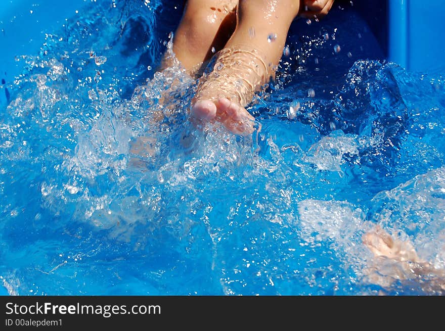 Close-up of boy kicking in kiddie pool. Close-up of boy kicking in kiddie pool.